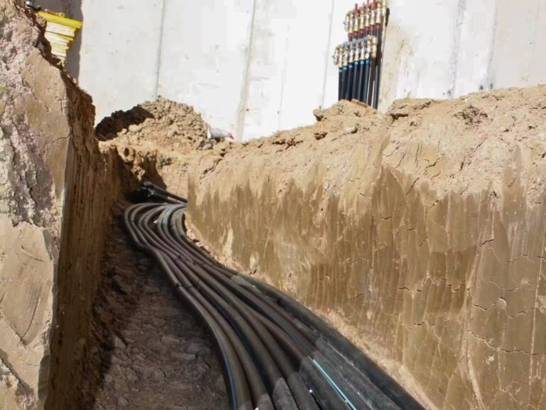 Instalación de canalizaciones subterráneas para sistema de climatización geotérmica en una zanja de obra.