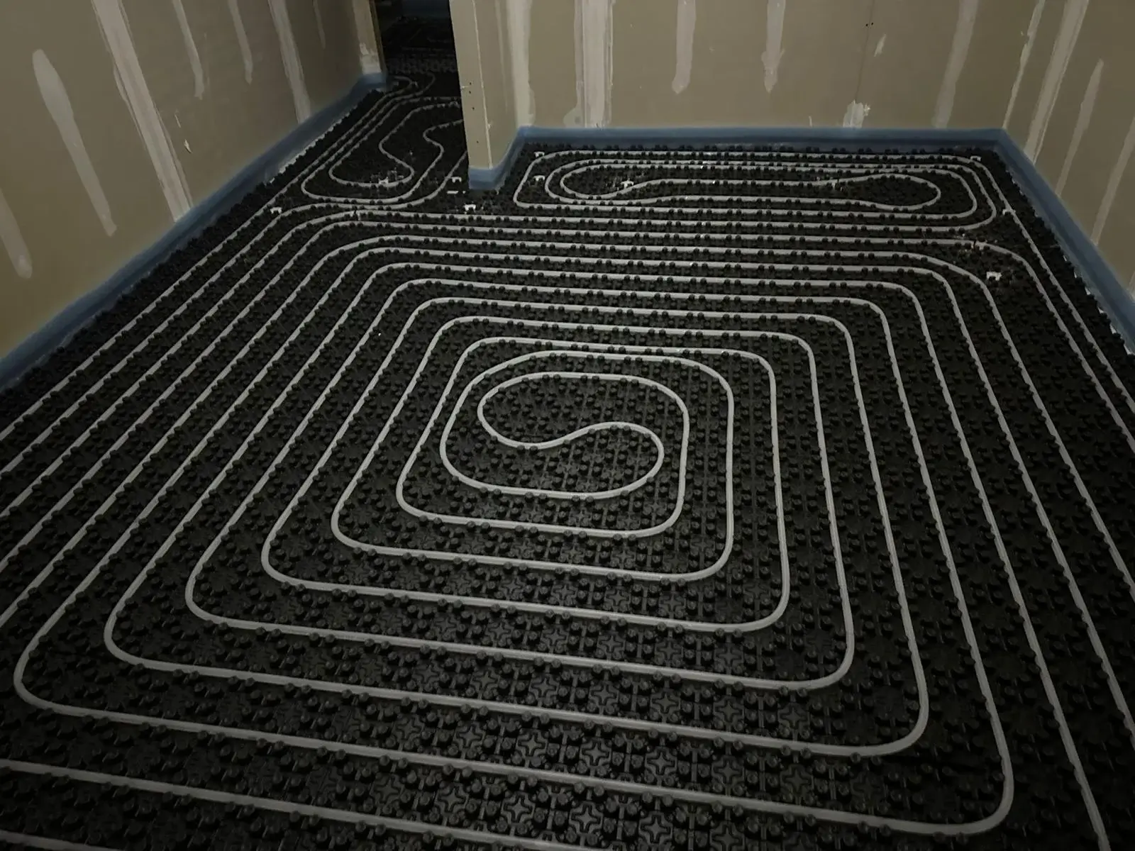 Material para suelo radiante. Vista de instalación de suelo radiante con patrón serpenteante en habitación en construcción